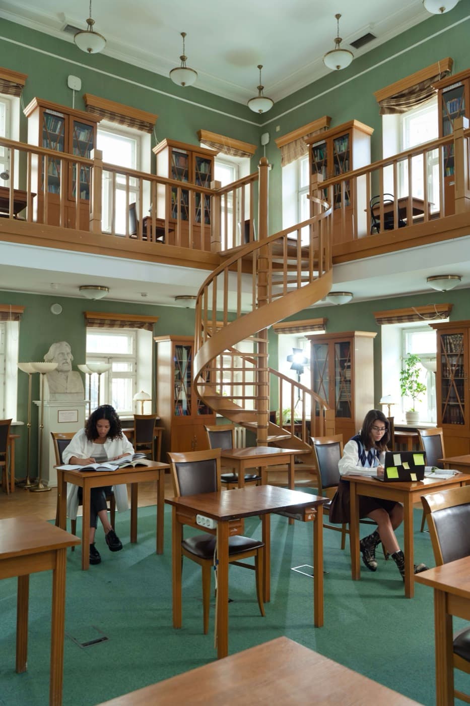 A galleried reading room with a spiral staircase and students at desks